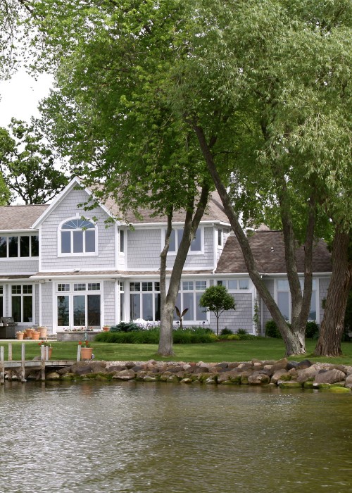 Large mature trees on residential waterfront property with lake and home.