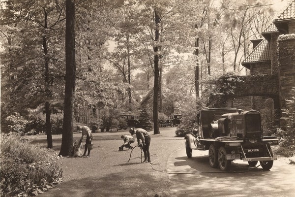 Historic black-and-white photo of ground crew servicing trees with vintage equipment truck.