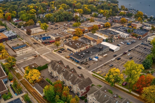Aerial view of downtown Excelsior with tree-lined streets and lake in distance.