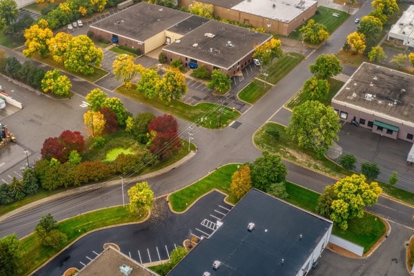 Aerial view of tree-lined commercial properties and parking lots in Plymouth, MN.