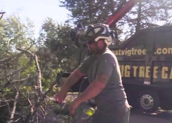 Ostvig ground crew member clearing storm debris with company truck in background.